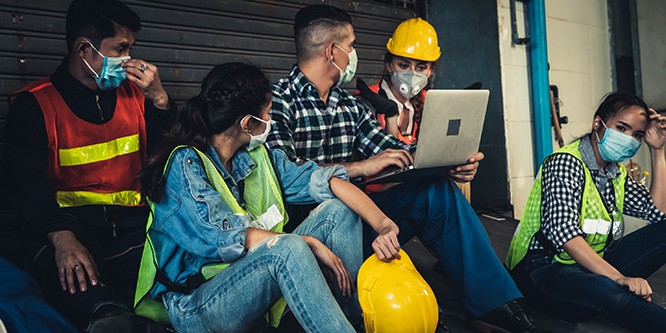 A pohot of workers sitting in a loading bay, looking at a laptop